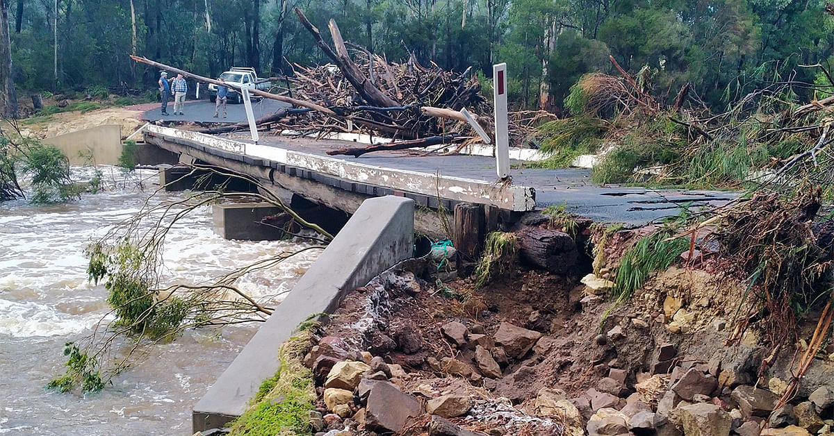 Flood water damage bridge, debris pillied high and bridge approaches washed away.