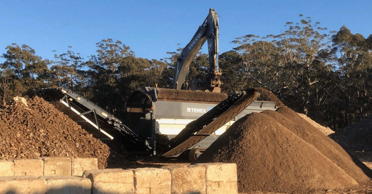 a concrete crushing machine on top of a concrete pile.