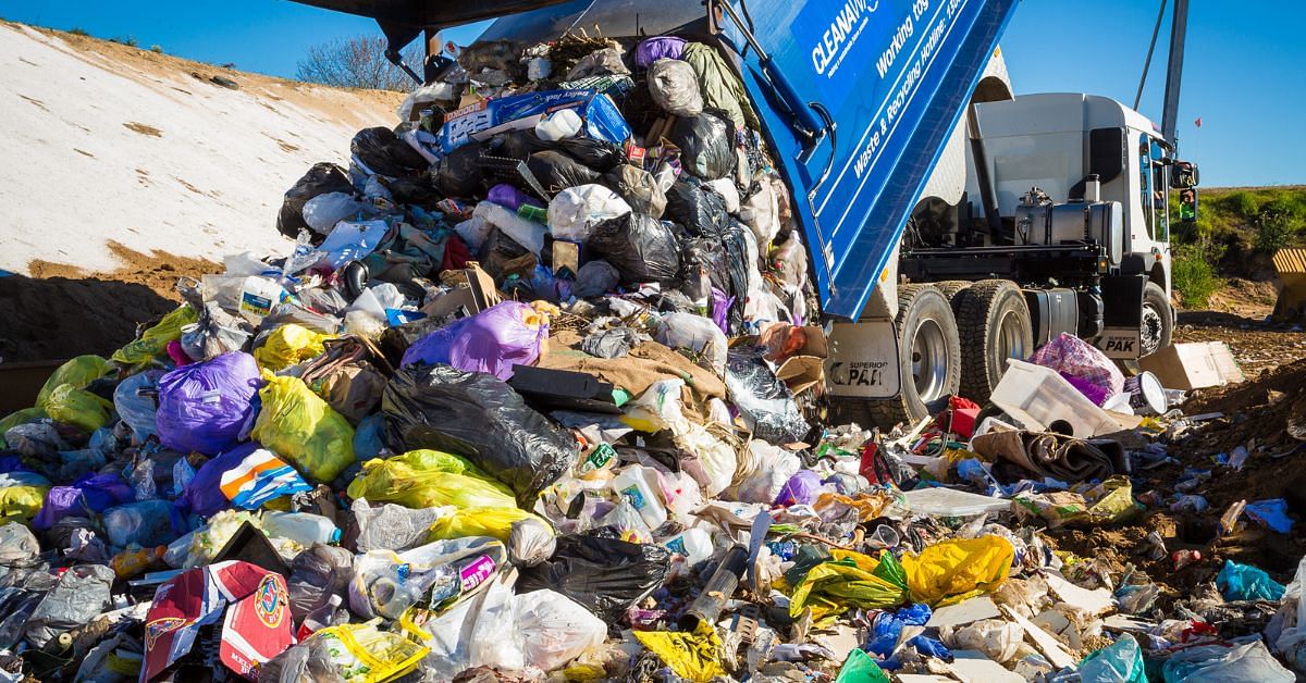 A garbage truck tipping a full load of rubbish while parked inside a landfill cell