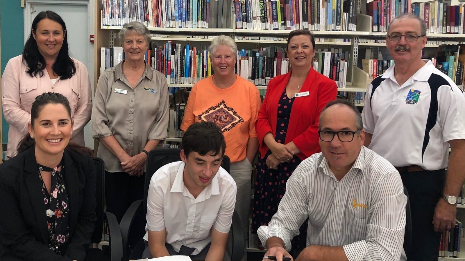 Sapphire Coast Anglican College student, Ben Cook completes the necessary administration and formalities at Bega Library with the many people who have helped the traineeship come to life. Top, from left: Leanne Slipper (Workability), Anne Moore (Bega Valley Shire Council Library), Kerrie Dalton (Ben's mother), Principal Tracey Gray (Sapphire Coast Anglican College), Richard Arbon (Sapphire Coast Anglican College). Seated, from left: Gemma Shinnick (Bega Valley Shire Council), Ben Cook; Glenn Vardanega (Apprenticeship Network Provider MEGT).