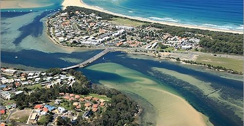 an aerial view of a lake dissected by a bridge and with houses in the foreground and background.