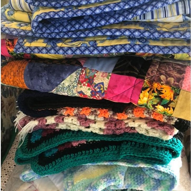 A pile of colourful hand made quilts.