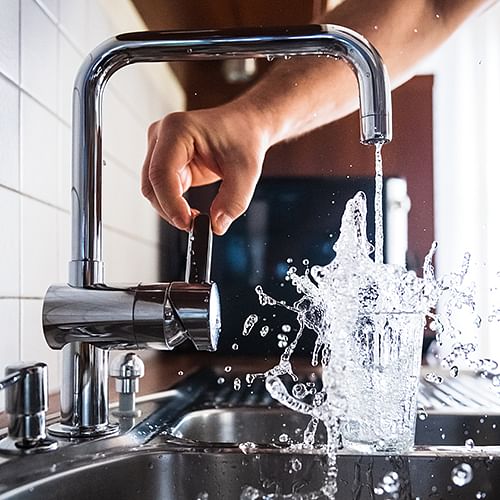 Water pouring from tap into glass.