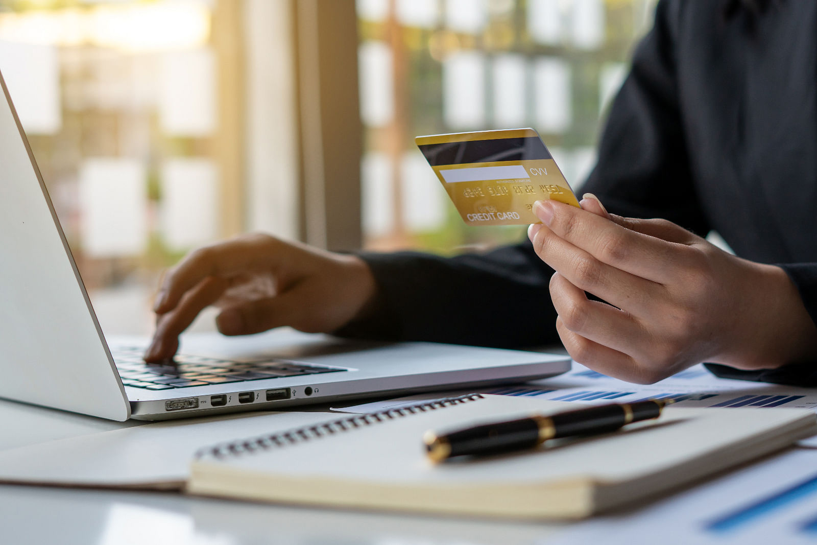 Laptop and hand holding credit card.